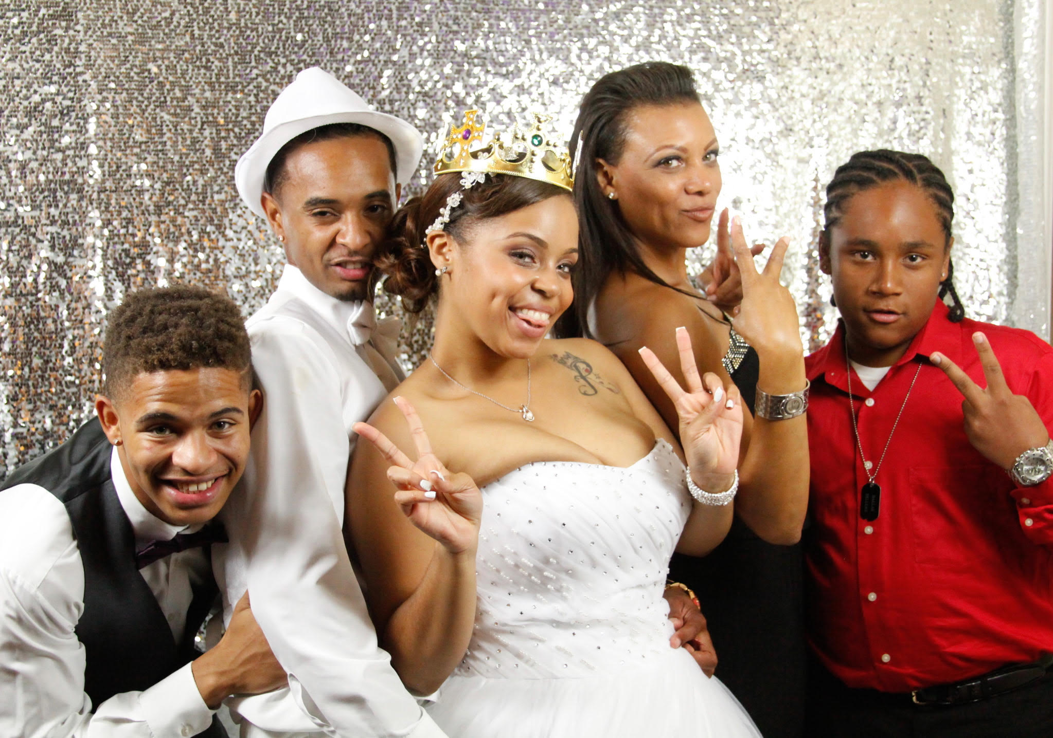 Wedding guests posing together with the bride in front of a sparkling backdrop